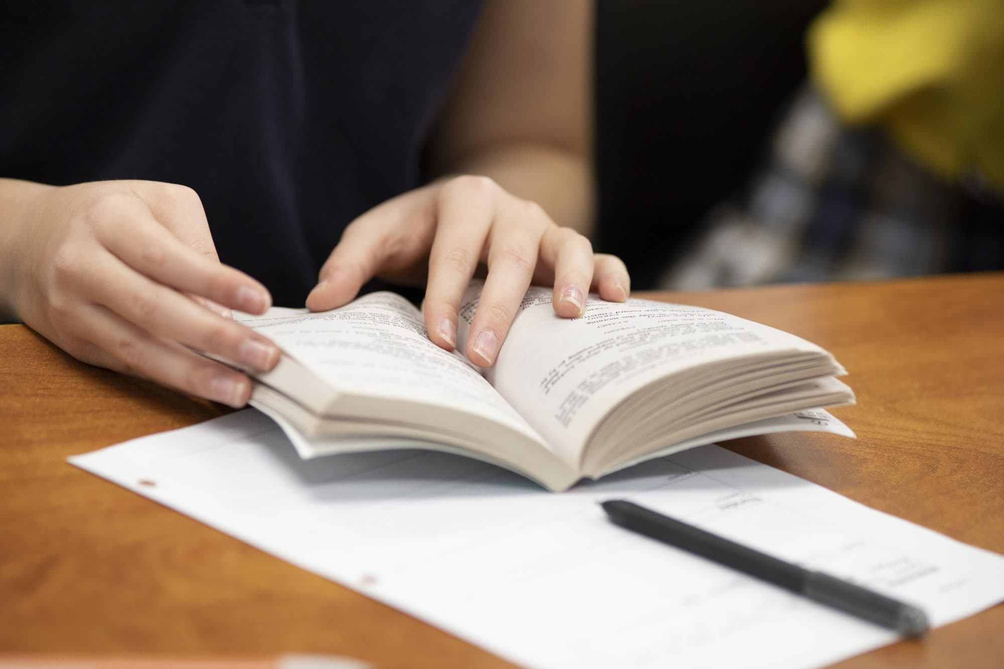 A Lincoln Prep student turning the pages of an open book