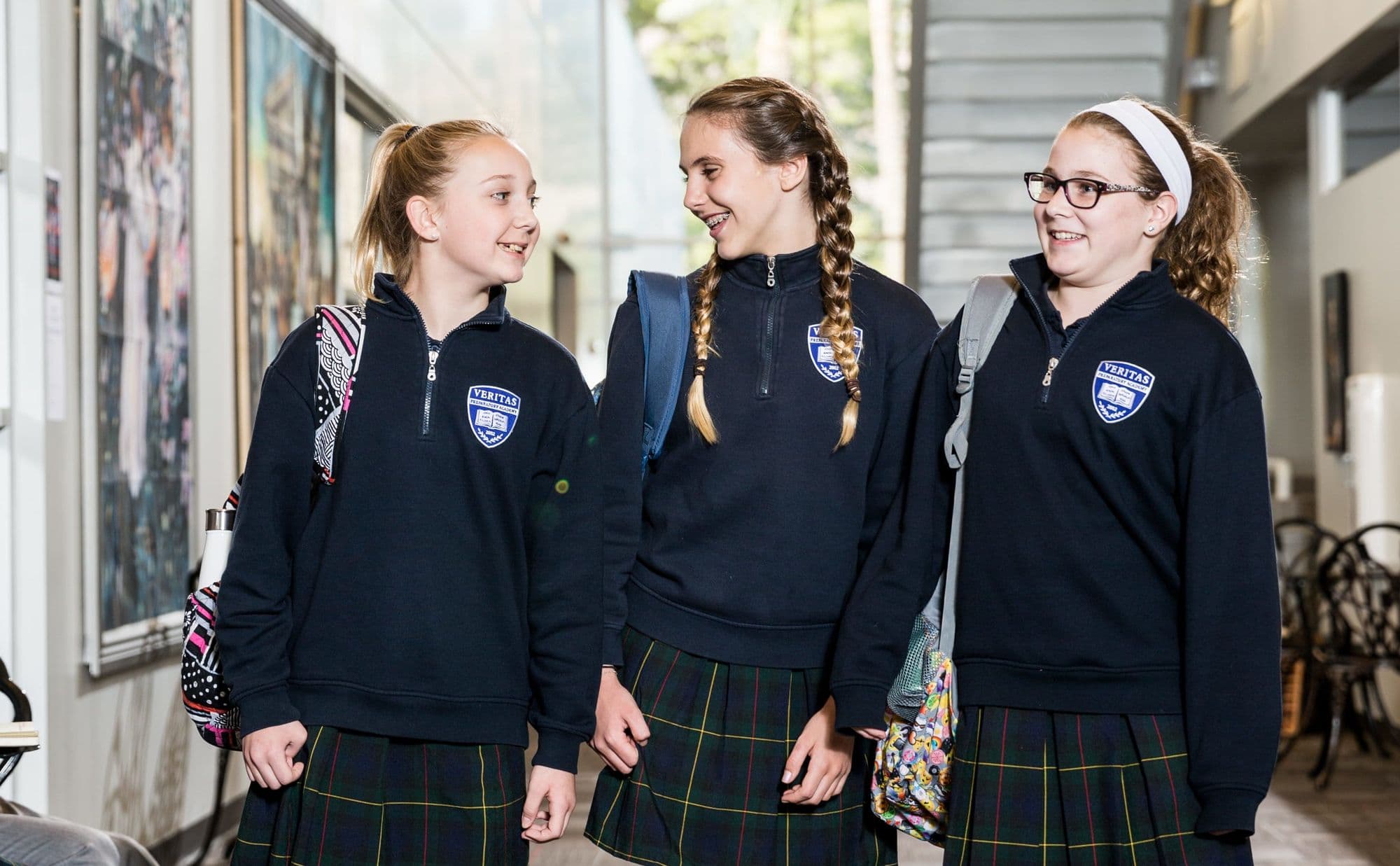 Three Veritas Prep students walking together through a campus hallway